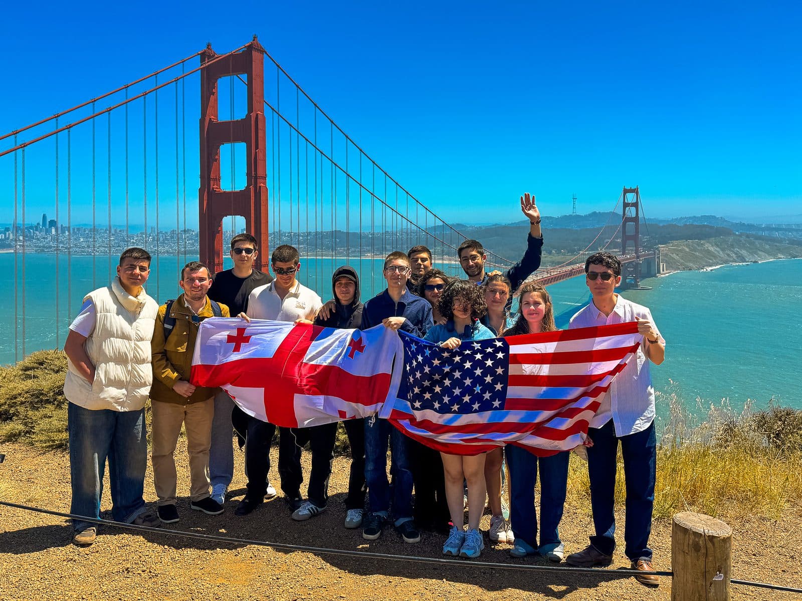 A TechExpedition group with Georgian and American flags above the Golden Gate Bridge
