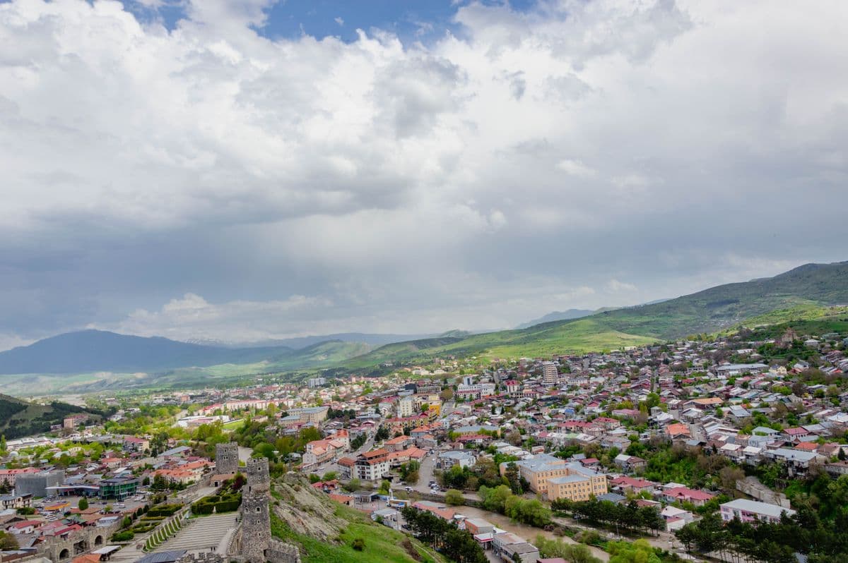 A wide view over the rooftops of Gori from the fortress hill, the old stone walls in the foreground and mountains beyond