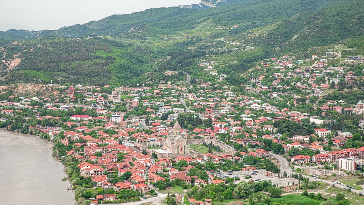სვეტიცხოველი და მისი გალავანი მცხეთის წითელკრამიტიან სახურავებს შორის, გვერდით კი მდინარე მიედინება